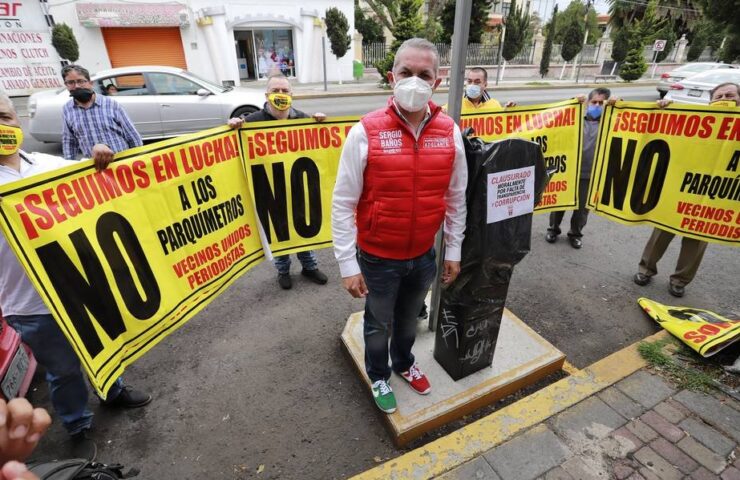 El presidente municipal de Pachuca, Sergio Baños posa frente a un parquímetro en Pachuca rodeado de varios vecinos